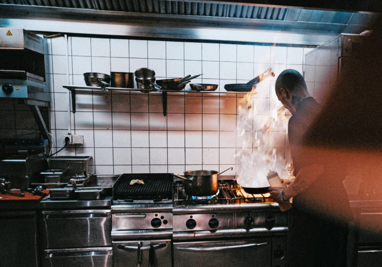 Kitchen staff tending flame over commercial canopy